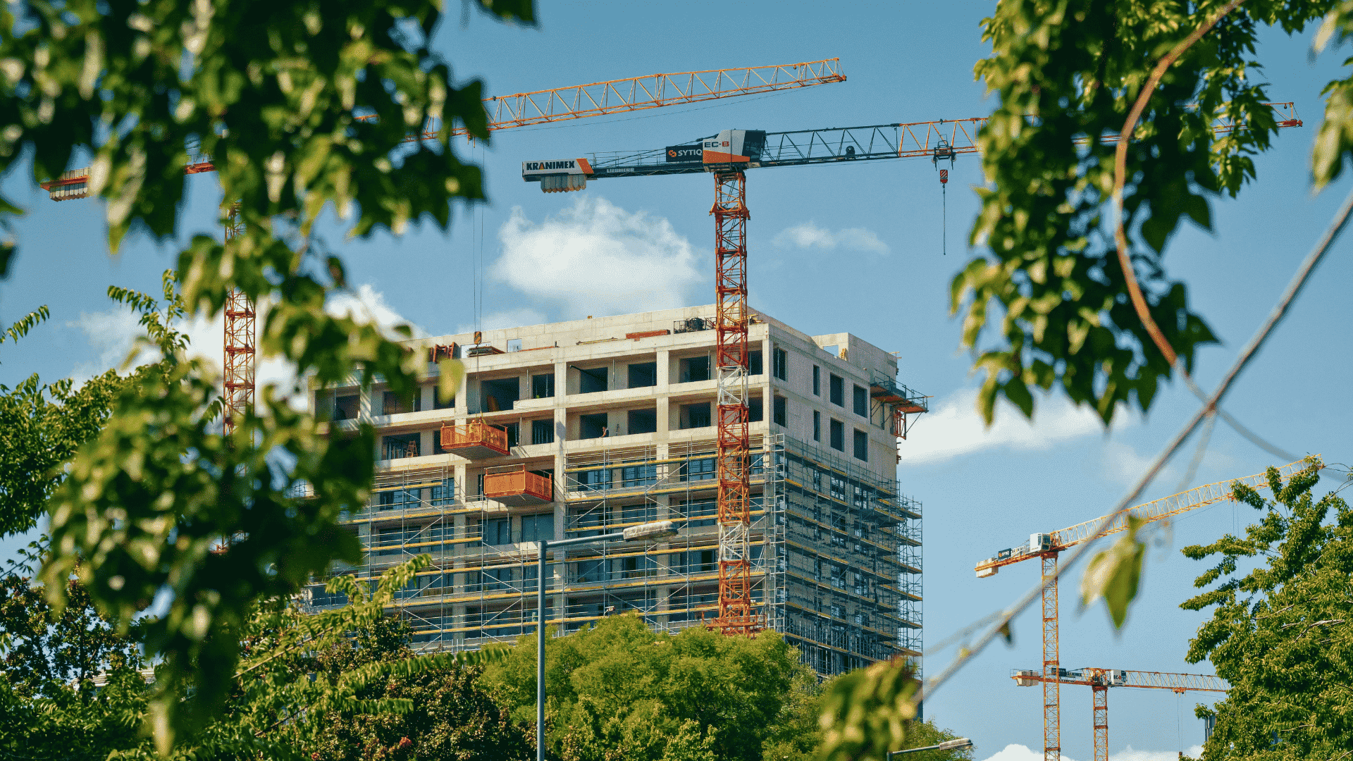 Edifício em construção com gruas, representando engenharia e construção sustentável